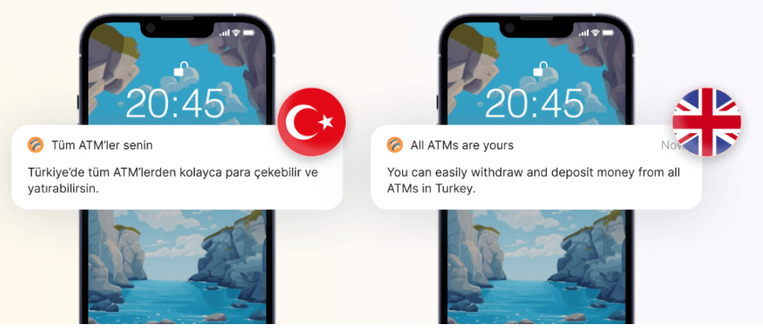 Two smartphones display the same push notification in Turkish and English, stating "All ATMs are yours." The screen shows a rocky coastal wallpaper, with Turkish and UK flags next to the alerts.